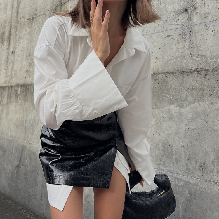 Nieuwe modieuze lente-outfit voor dames 2026: een complete set bestaande uit een eenvoudige, losse witte blouse en een kort rokje met tailleband._voghion.com