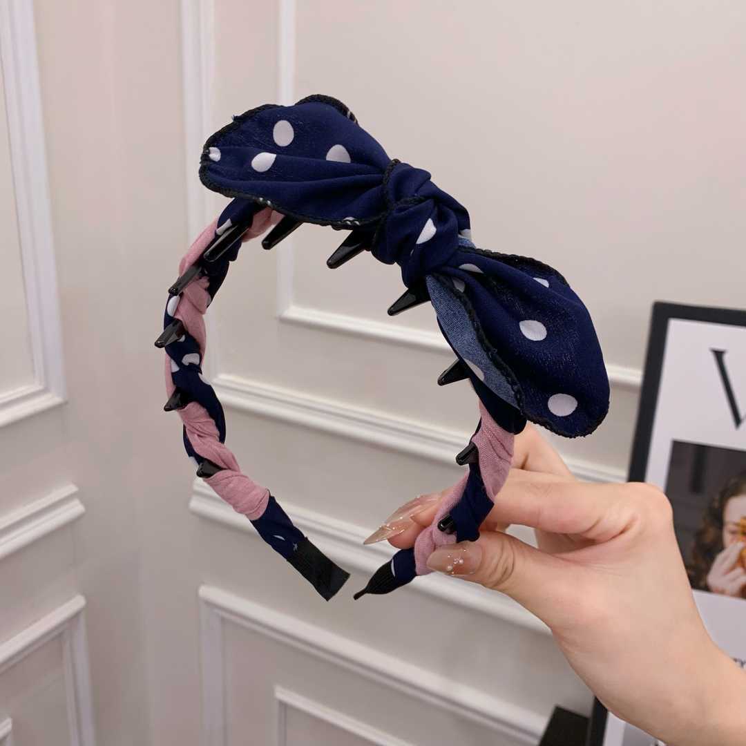 A navy blue polka dot contrasting rabbit ear comb headband