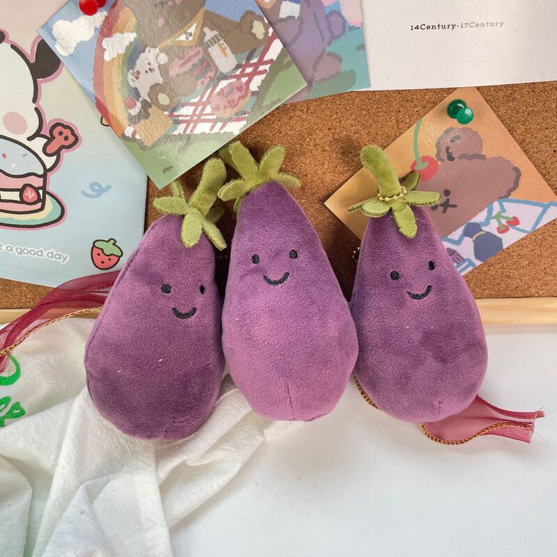 かわいい超萌えナスのほほえみ野菜の表情はぬいぐるみの息子の包みのペンダントのゲーム城を包んで子供のプレゼントをつかみます。|undefined