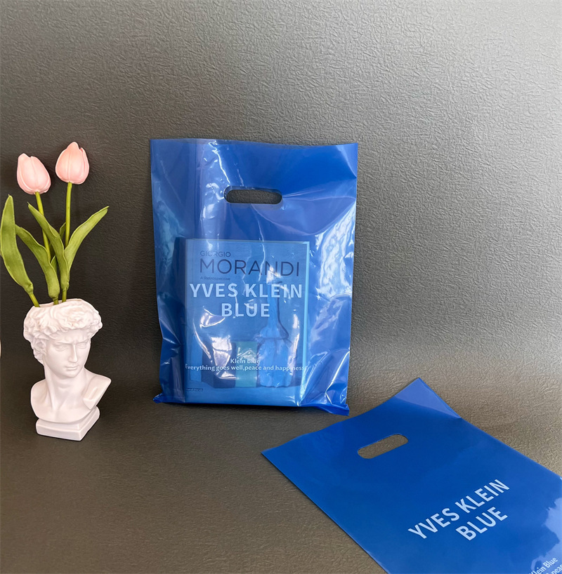 子供服の店の手提げ袋のプラスチックを持って、透明な四本の指を厚くします。