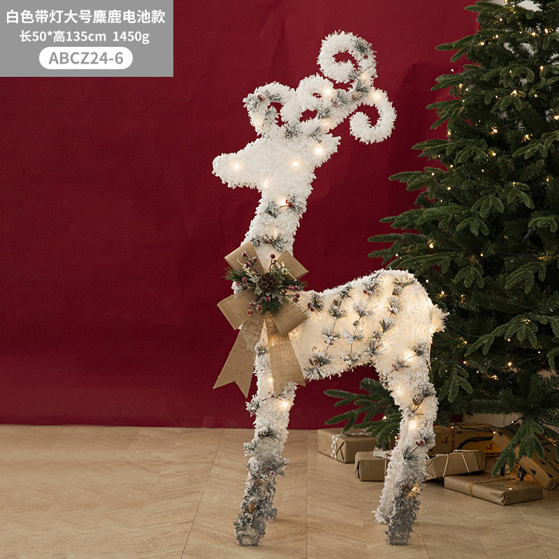 Decoraciones navideñas de muñecos de nieve, adornos de escaparate con una escena de renos de peluche blancos brillantes para la Nochebuena.