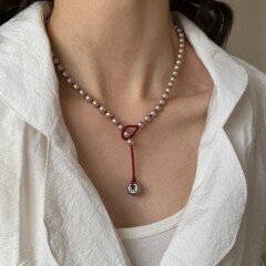 新年の赤いシャンパンの金の細いきらめきの真珠のビーズのネックレスは百合して古い風のペンダントをします。