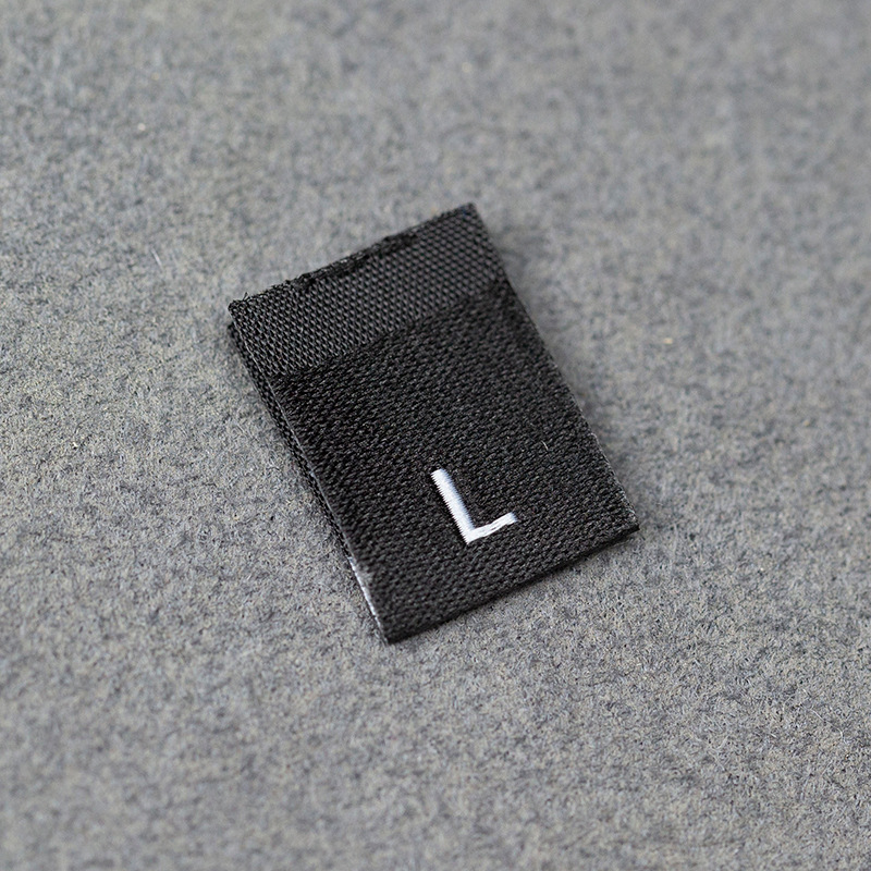En stock Etiqueta de tamaño de alta densidad en blanco y negro Etiqueta de tamaño universal Etiqueta de código de letra inglesa Pantalones Etiqueta de código de cuello de camiseta