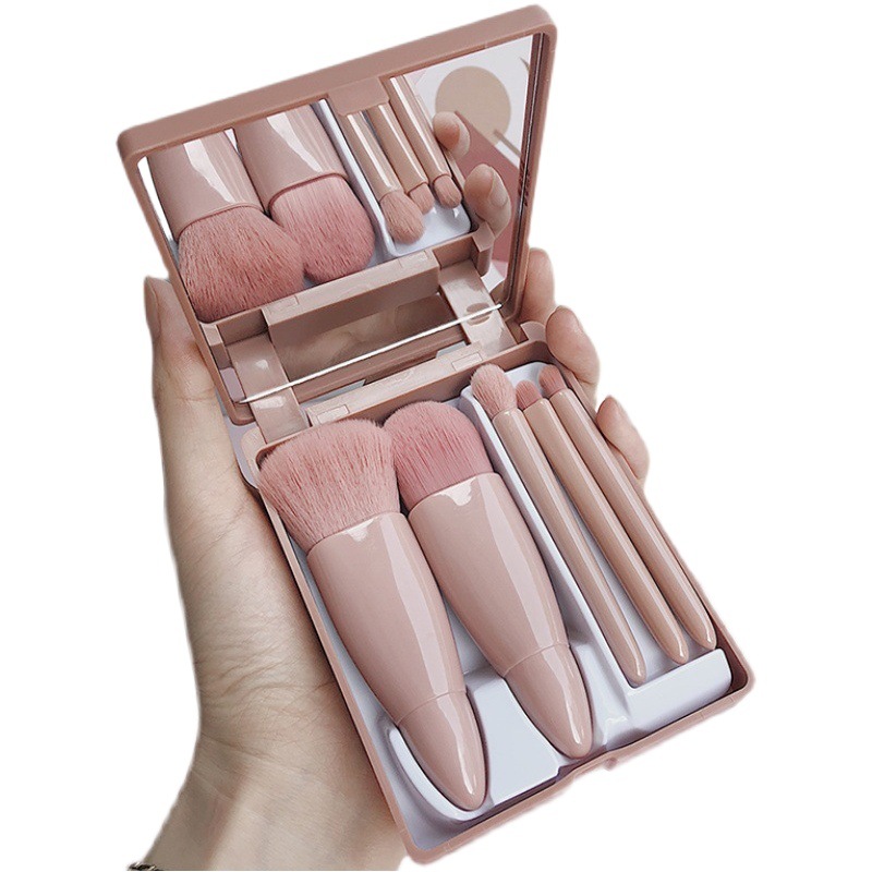 Un juego de 5 brochas de maquillaje portátiles en una caja con estuche con espejo, que incluye una brocha para base, una brocha para labios, una brocha para sombras de ojos, una brocha para polvos sueltos y un almacenamiento para productos de belleza.