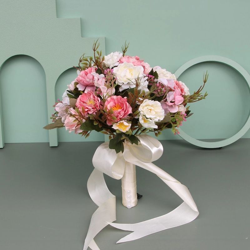 手に花を持つ新婦の韓国式結婚式の領収書のシミュレーションの花束の森系のウェディングドレスの撮影の道具の手に花をささげます。|undefined