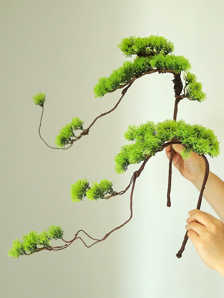 Добро пожаловать в сосновые ветви, искусственные мертвые лозы, стволы сосен, листья тюи, гостиничные тарелочные лампы, китайские цветочные композиции, декоративные зеленые растения.