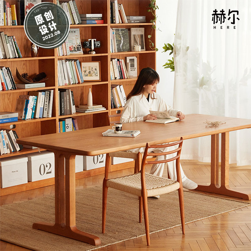 The mailman knocks on the door. The living room has a large wooden desk as a workbench, and a cherry wood dining table with a double-sided desk.