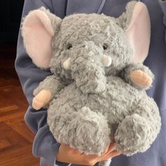かわいい怠惰な象のぬいぐるみのぬいぐるみがベッドに寝ている子供の赤ちゃんの人形が誕生日プレゼントの女の子をなだめる