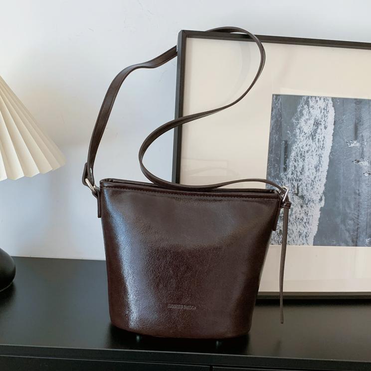 Bolsos de mano retro de alta textura para mujeres 2025, nuevos bolsos de hombro de moda simples, bolsos de cubo de transporte universal