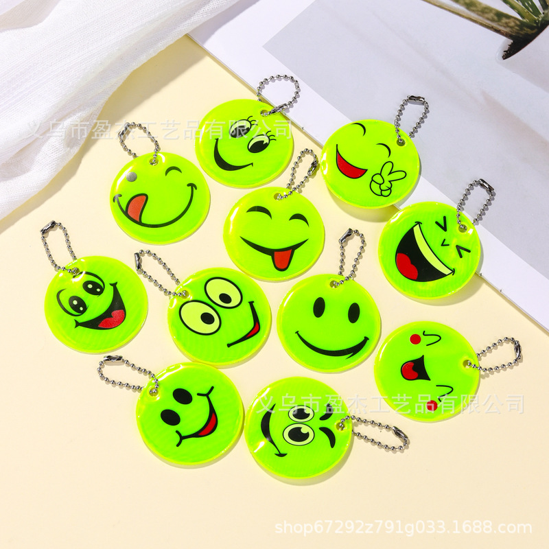 Muchos colgantes reflectantes transfronterizos sonrientes para niños viajan por la noche PVC seguro al aire libre