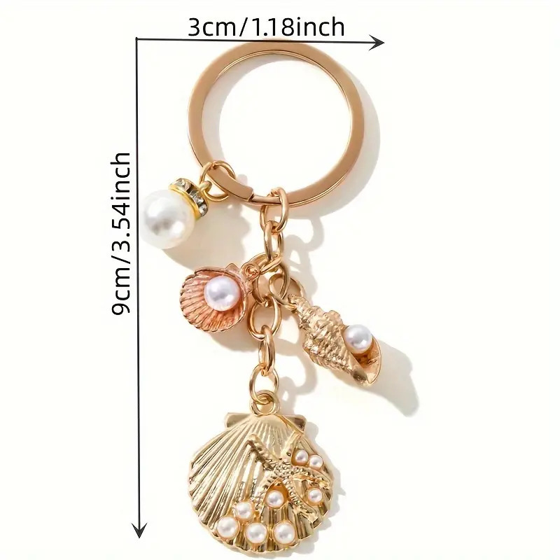 An elegant gold seashells and faux pearl keychain with sea-inspired enamel charm and conch charm