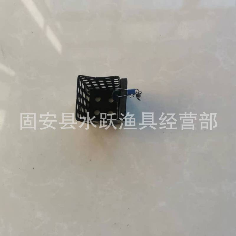 黒い四角形の丸い鉄の餌のかごに餌の道具が付いています。|undefined