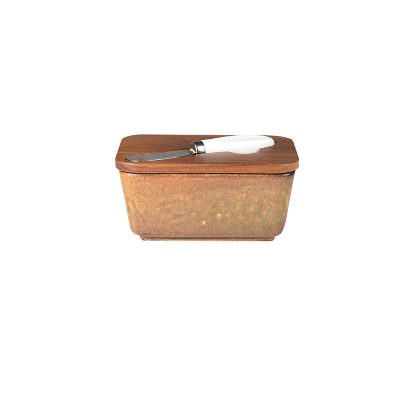 Mantequillera de cerámica con tapa de madera y cuchillo, apta para uso alimentario.