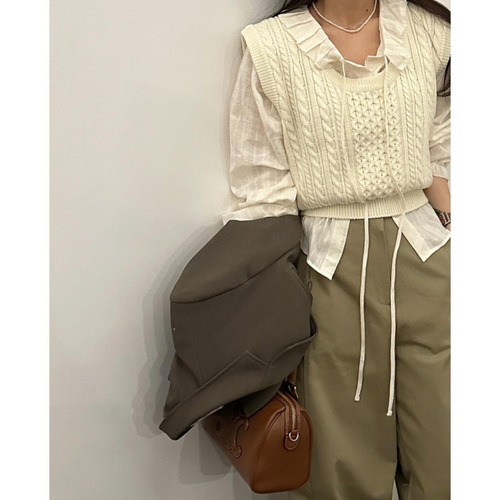 White long-sleeved shirt with floral lace and ribbon details, featuring a sweet chic early autumn vibe, paired with a knitted cabled vest.