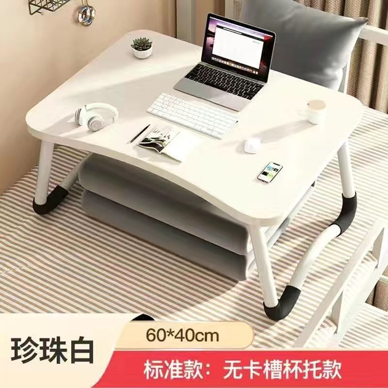 ベッドの上の小さい机のノートパソコンの机の上で折り畳みます。|undefined
