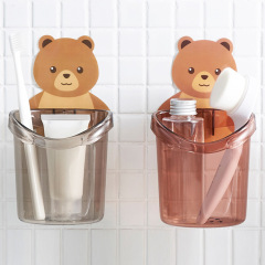 トイレの熊は歯ブラシのコップの歯磨き粉の収納棚を抱いています。