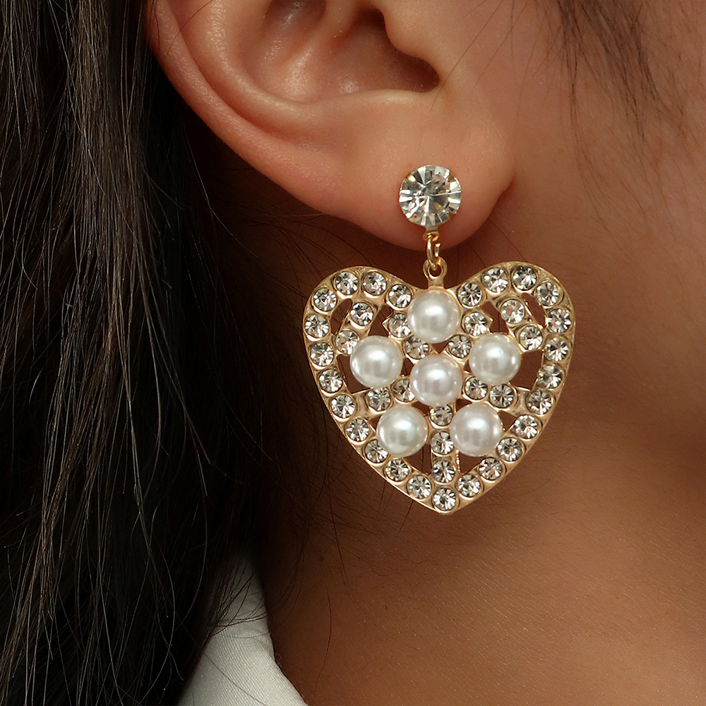 Fashion Hollow Heart Shaped Inlaid Pearl Diamond Metal Drop Earrings display picture 1