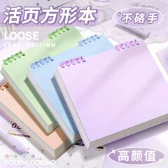 正方形のルーズリーフのノートのグリッドの方眼本の高い顔の値のルーズリーフの上でひっくり返して手の帳簿のノートを取り外します。