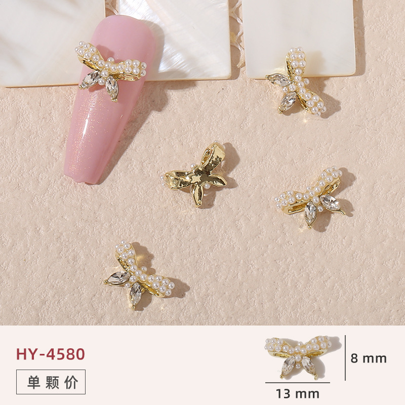 Uñas mariposa joyería nueva línea popular perla arco metal decoración de uñas pequeños accesorios de joyería al por mayor