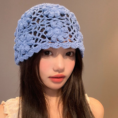 民族風の手作りのかぎ針の花の青いニットの帽子の女性の春の夏の旅行は写真を撮ります。