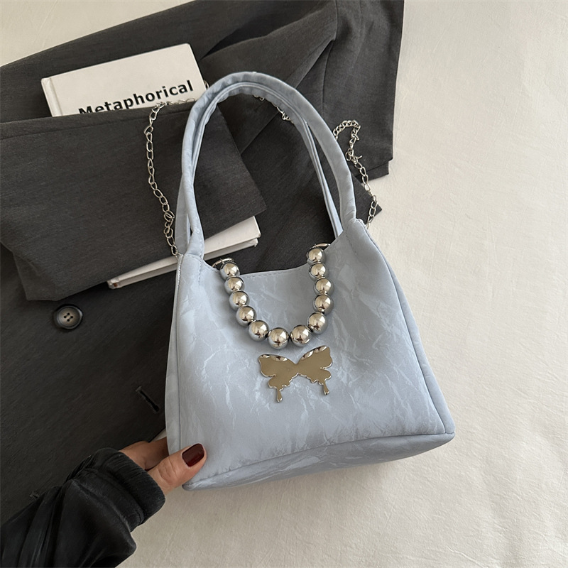 Alta sensación de lujo ligero bolso de cubo axilar 2024 verano nuevo estilo de moda arco de cuentas cadena de hombro mochila