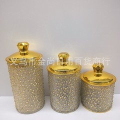 金色の真珠の貯蔵タンクのテーブルの上にナッツのキャンデーの缶のホテルのお茶の缶の置物を持ちます。