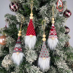 クリスマスの小人の老人は北欧風の顔のない人形を飾ります。