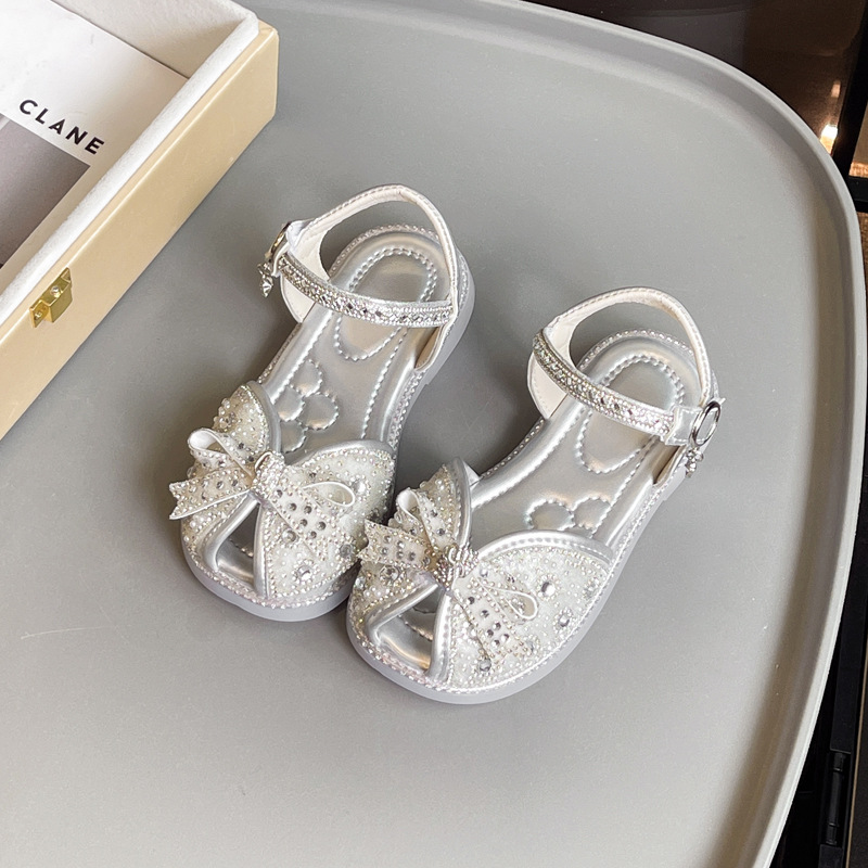 Sandalias Baotou para niñas 2025 verano nuevo estilo bowknot moda cristal princesa zapatos de playa para niños de suela suave marea