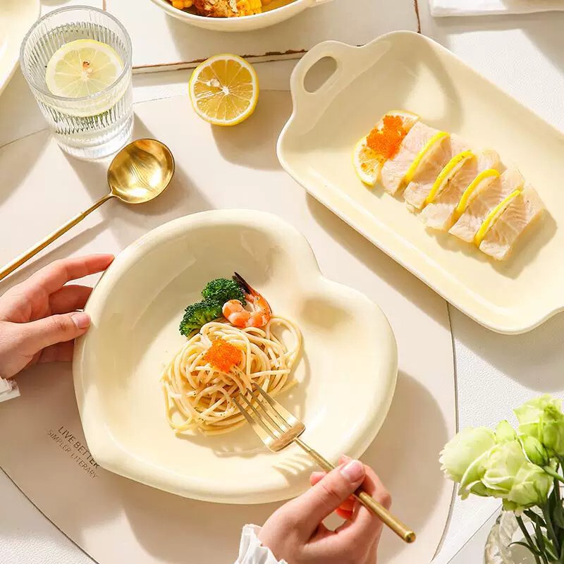 Creamy, understated ceramic tableware set with underglaze decoration, featuring a French-style design, uniquely shaped bowls with double handles, heart-shaped plates, and rice bowls Creamy, understated ceramic tableware set with underglaze decoration, featuring a French-style design, uniquely shaped bowls with double handles, heart-shaped plates, and rice bowls