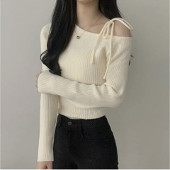 秋の小衆のレトロな中に、底のシャツの上着の斜めの襟の肩の結び目を着て、スリムな長袖のニットのセーターの女性を見せます。