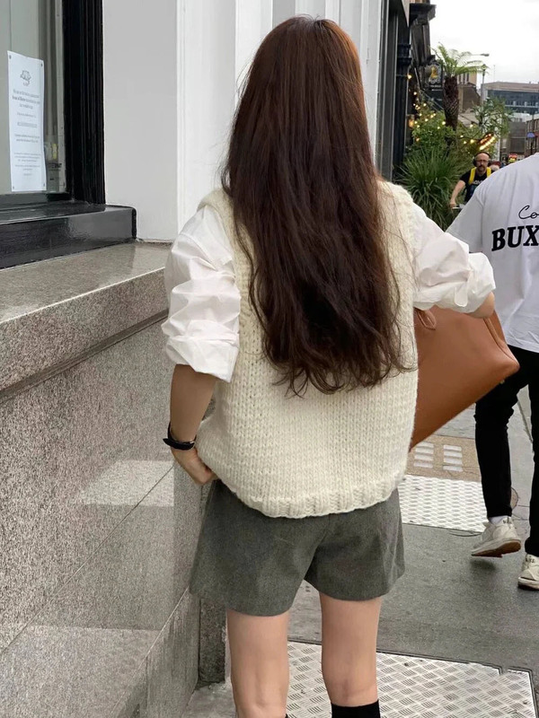 柔らかいモチのレトロな白いニットのベストの女性は秋冬に肩のセーターのベストを重ねて着ます。|undefined