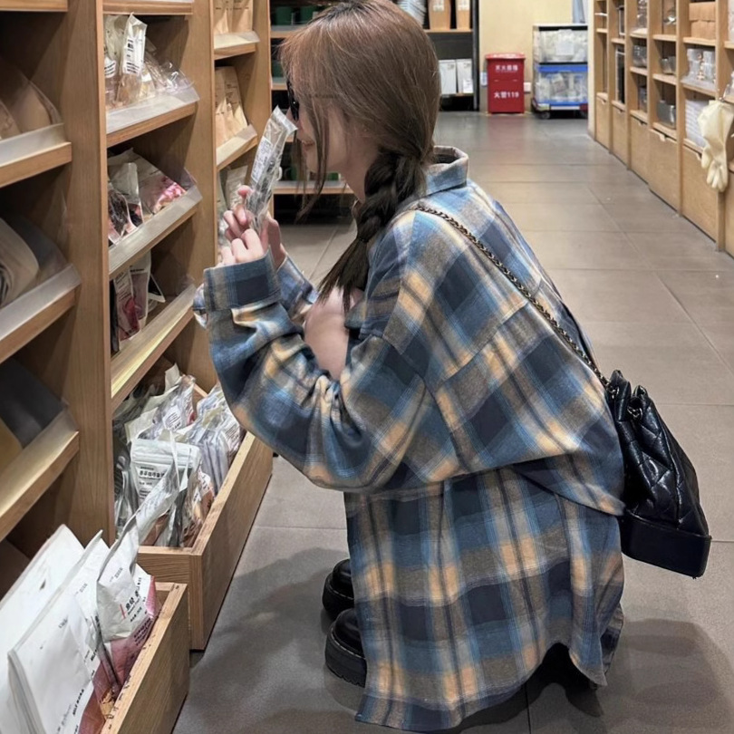 レトロな韓国の格子のシャツの女性の新型の香港風のカジュアルなファッションのデザイン感のシャツの百合は底の長袖のコートを打ちます。