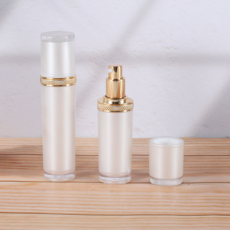 Botella acrílica blanca perlada para crema o loción, diseño con tapa dorada tipo diamante, recargable y elegante.