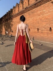 タイの休暇の赤い背中のストラップのワンピースの女性の海辺の旅行は写真を撮るのに適したロングスカートの夏を着ます。