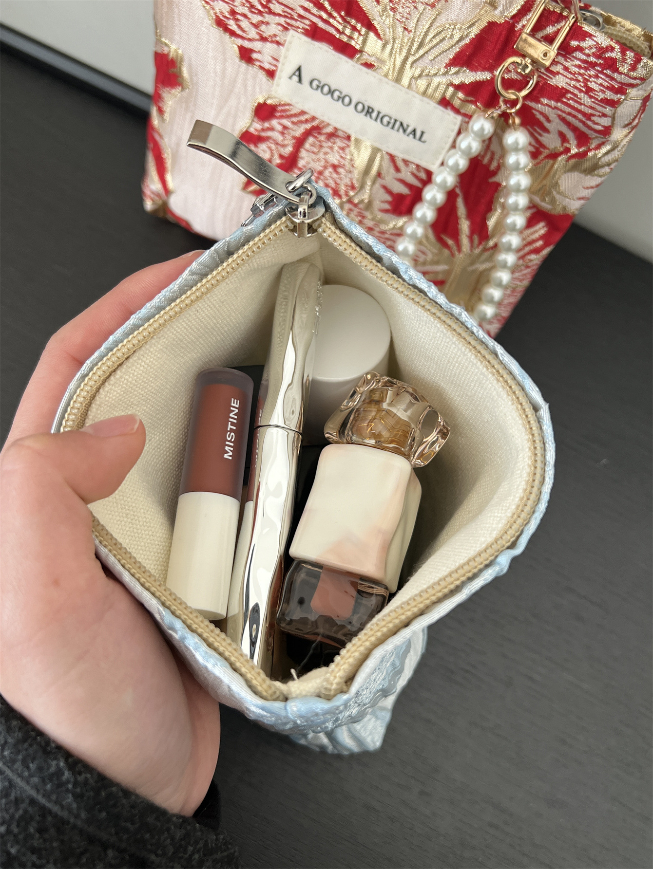 トランペットの高級感のある手は化粧バッグを持っています。布芸の財布を持っています。