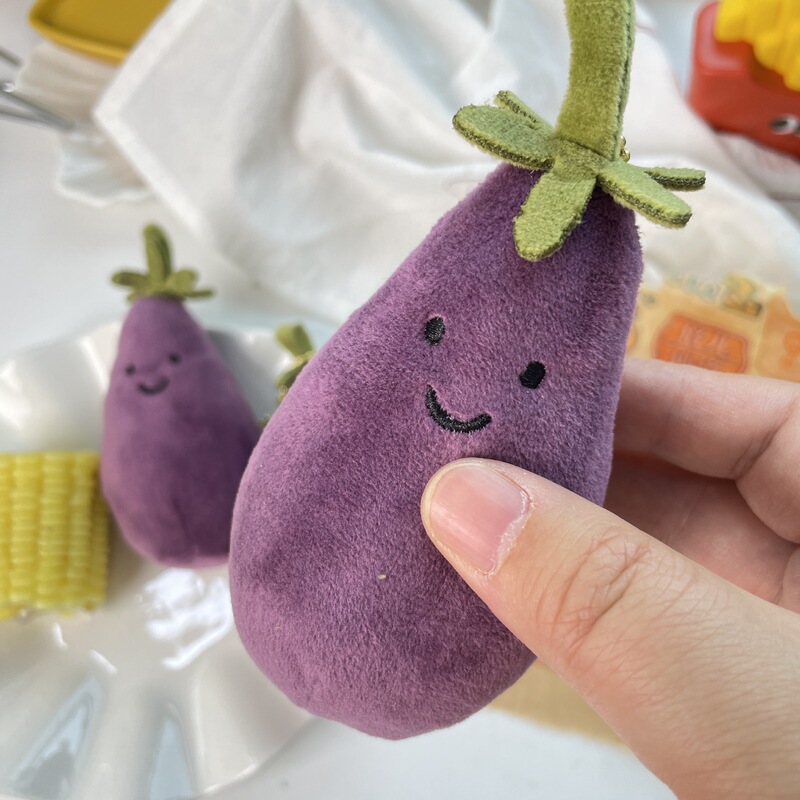 かわいい超萌えナスのほほえみ野菜の表情はぬいぐるみの息子の包みのペンダントのゲーム城を包んで子供のプレゼントをつかみます。|undefined