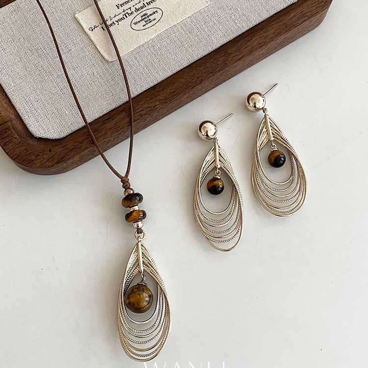 Autumn and winter retro tiger's eye stone and golden feather pendant earrings and necklace, a high-end, lightweight, and unique accessory set for sweaters
