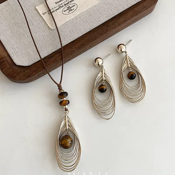 Autumn and winter retro tiger's eye stone and golden feather pendant earrings and necklace, a high-end, lightweight, and unique accessory set for sweaters