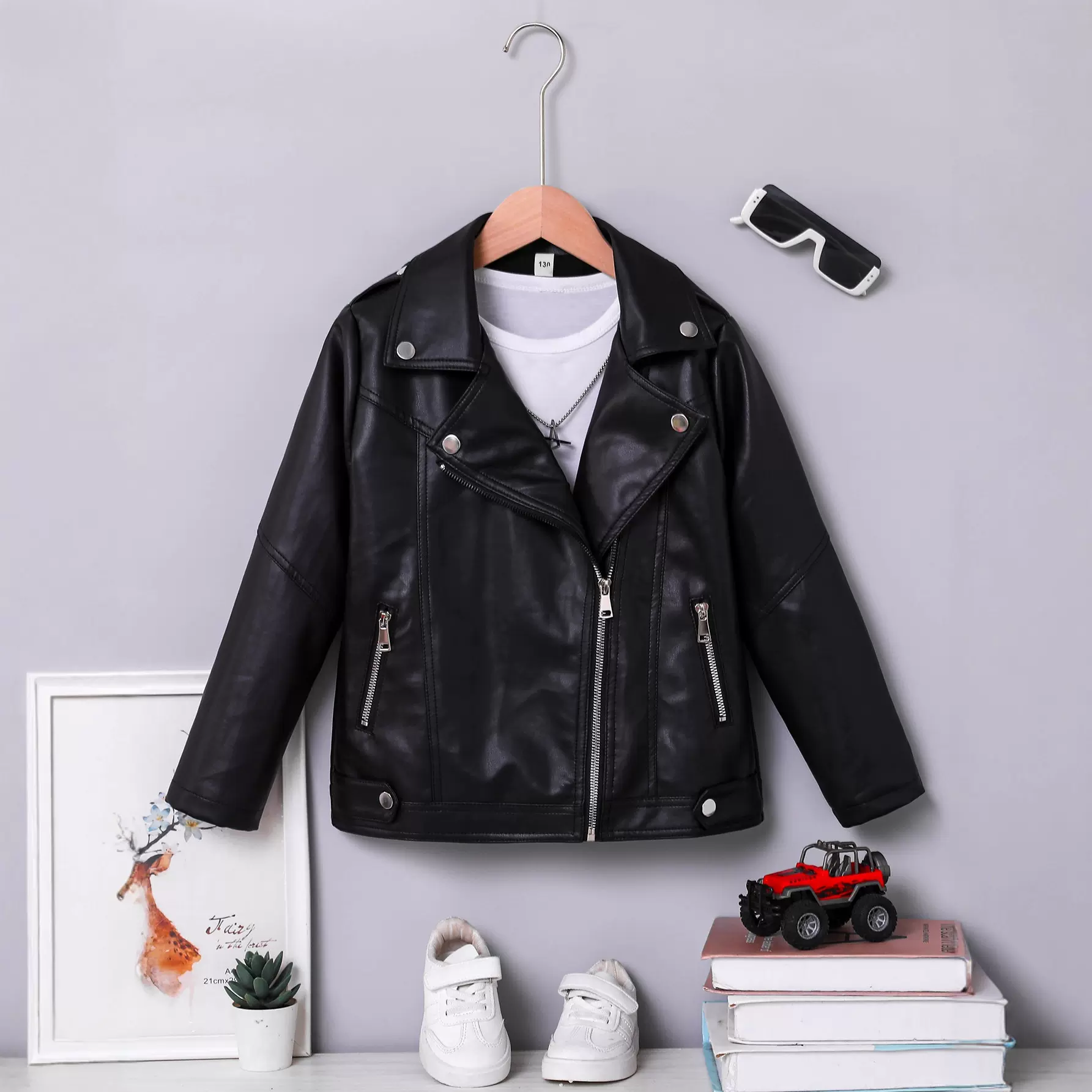 黑色儿童皮夹克，采用经典机车设计，搭配银色金属拉链和铆钉
