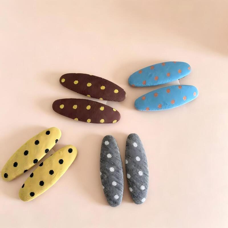Retro polka dot oval-shaped hair clips for women, featuring a simple fabric design, perfect for securing side bangs and adding a fresh, versatile touch to your hairstyle