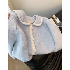 甘くて優しい牛の角は青いセーターのカーディガンの女性のゆったりした短いタイプの春の服を掛けます。