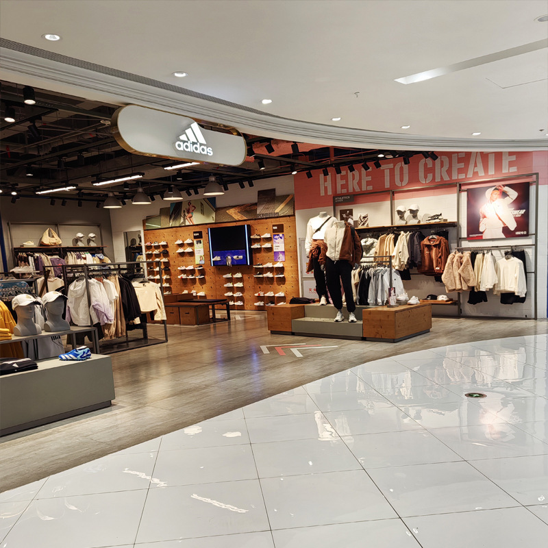 Tienda de descuento de ropa en la pared estante de exhibición deportivo estante de piso con lámpara en la isla de zapatos nuevos productos de pared