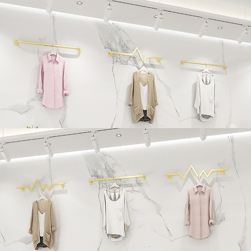 Display racks for women's clothing stores, wall-mounted hangers in black and gold, horizontal bars on the wall with clothes hanging on the rods