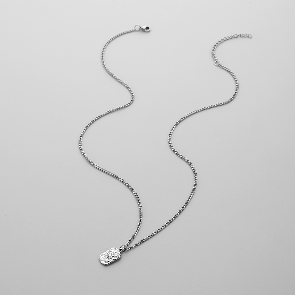 Collar con colgante cuadrado de plata para hombres, con una cadena de plata y un colgante pequeño con forma ovalada que muestra un intrincado patrón tipo estallido de estrellas.