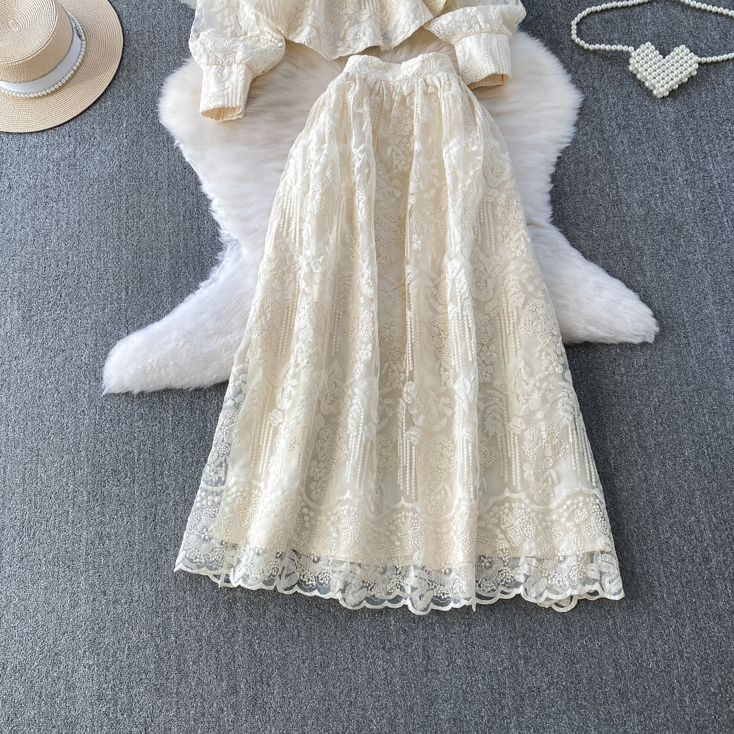 Ensemble deux pièces sophistiqué pour femme : jupe taille haute et chemisier brodé transparent. Coupe cintrée, charme féminin délicat._voghion.com